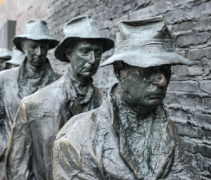 Statutes of men next to a brick wall from the front
