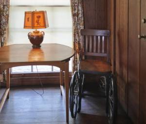 A photo of President Franklin Delano Roosevelt's wheelchair next to a table with a lamp
